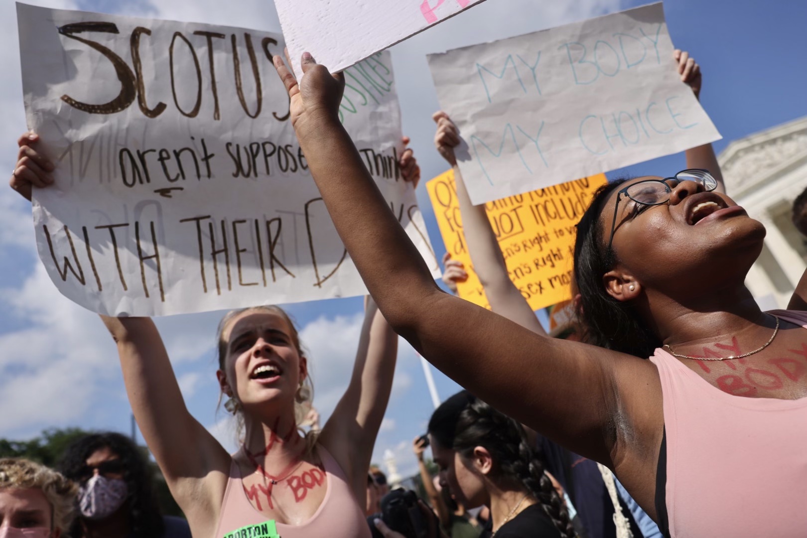 Two pro-choice demonstrators hold up signs in from of the Supreme Court.
