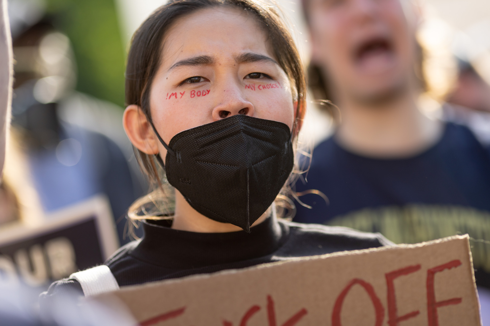 A masked demonstrator with the words "my body, my choice" under their eyes.