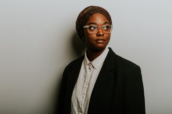 Headshot of Oklahoma State Representative Mauree Turner with a neutral expression. They are wearing a scarf on their head, a black blazer, and a white button-down shirt.