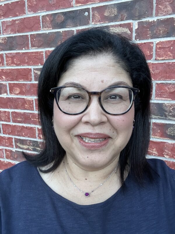 Headshot of librarian Becky Calzada smiling. She is wearing black, round glasses and a dark blue blouse.