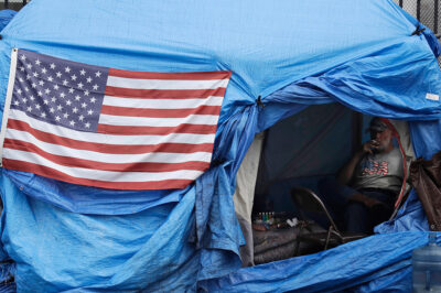A man smokes inside a tent on skid row Friday, March 20, 2020, in Los Angeles.