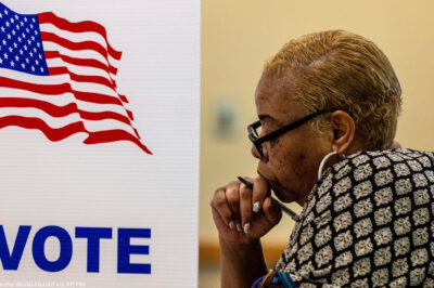 A profile view of a woman in a voting booth.