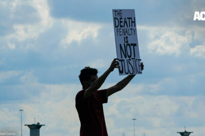 A man holding a sign that says "Death Penalty is Not Justice."