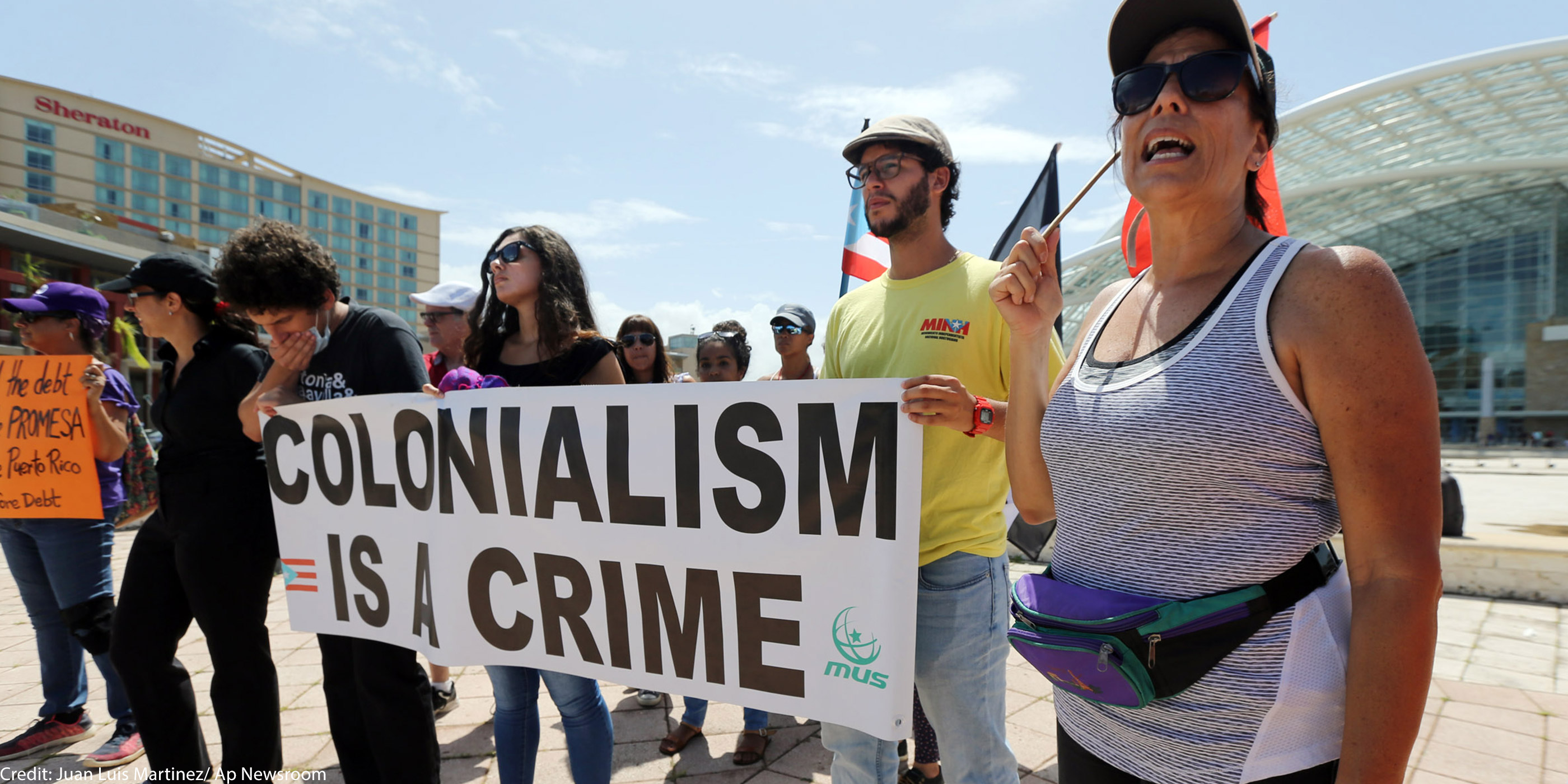 Individuals holding a sign that says Colonialism is a Crime.