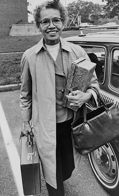 Pauli Murray holding a briefcase next to a car