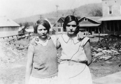 Black and white image of two girls with their arms around each other.