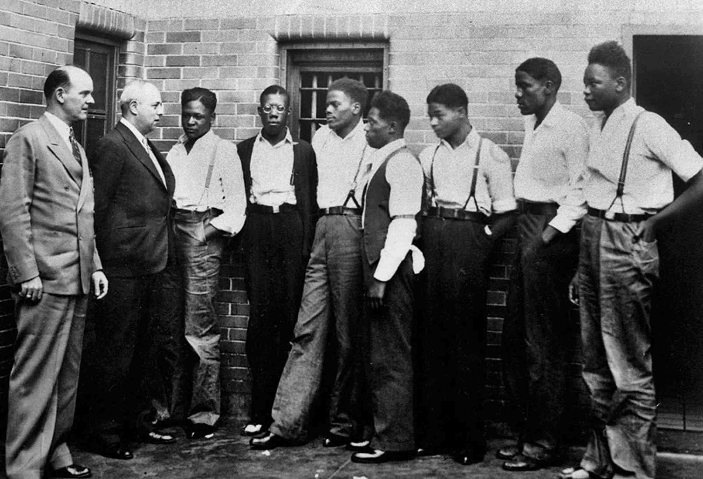 A black and white photo of seven Scottsboro defendants and two attorneys standing.