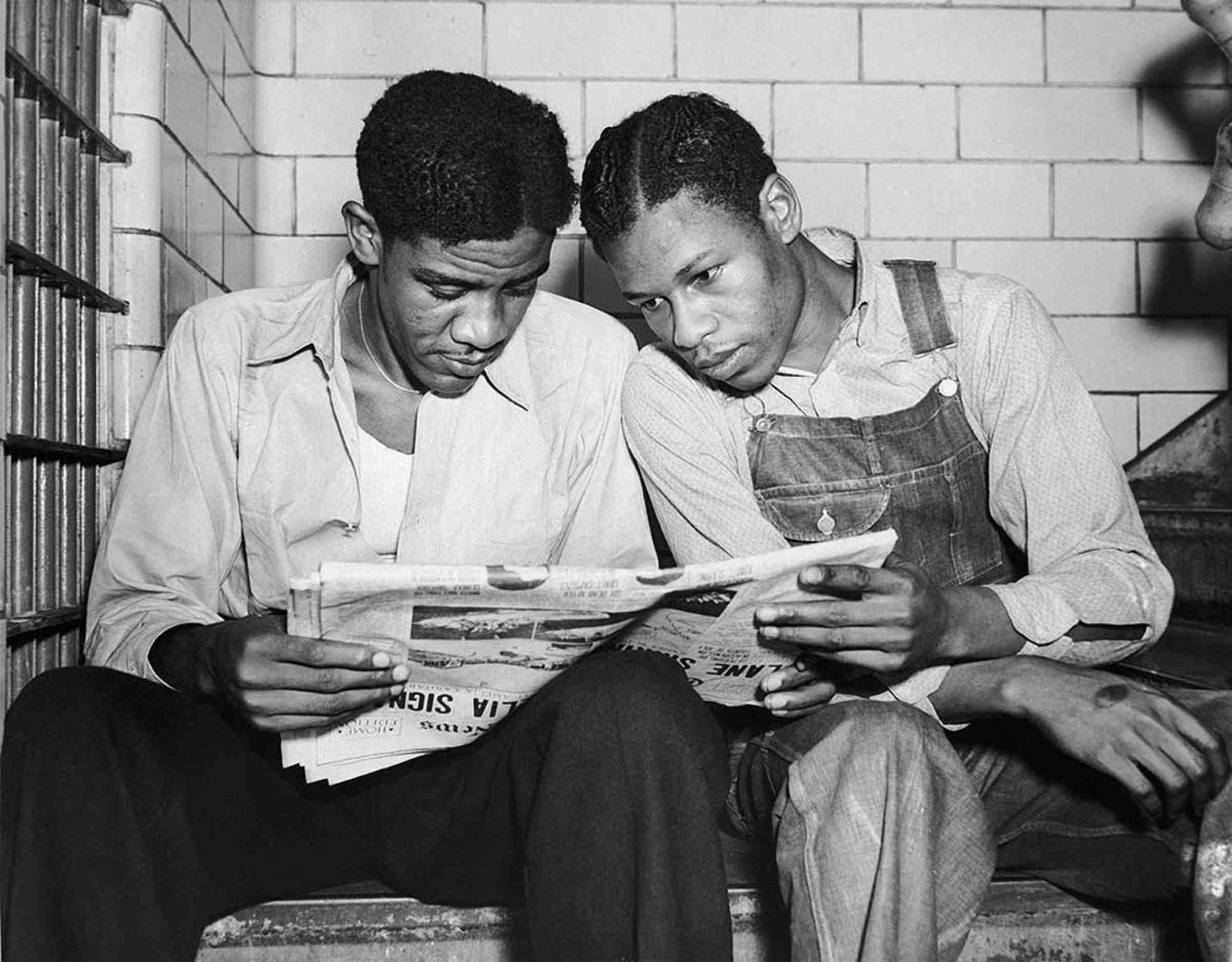 A black and white photo of two Scottsboro defendants sitting and reading a newspaper.