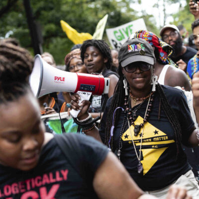 A group of Black marchers holding signs and a megaphone.