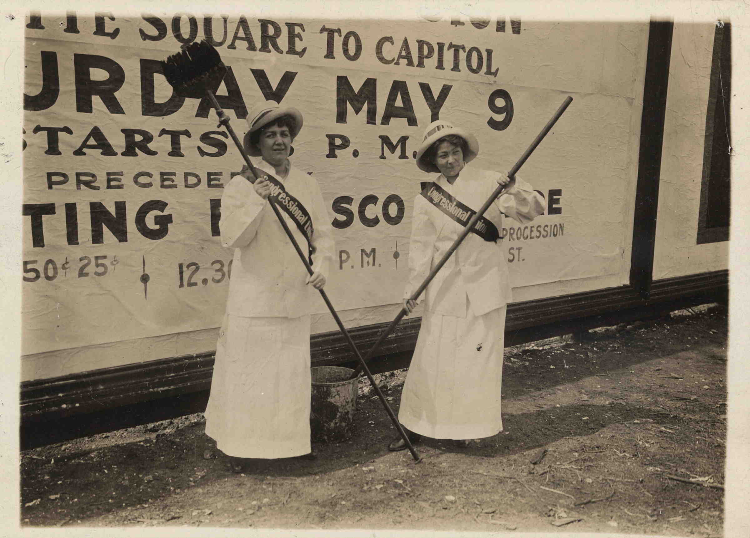 Two women pasting large advertisements