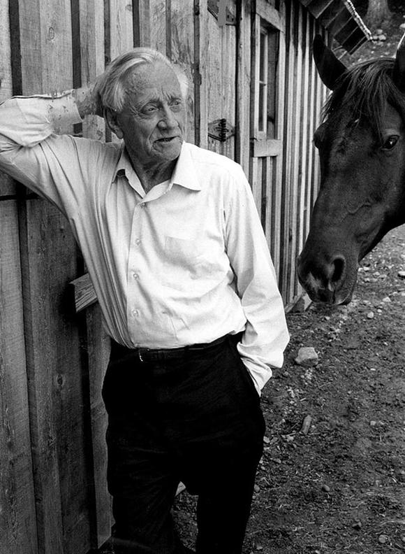 William O. Douglas leaning against a fence next to a horse