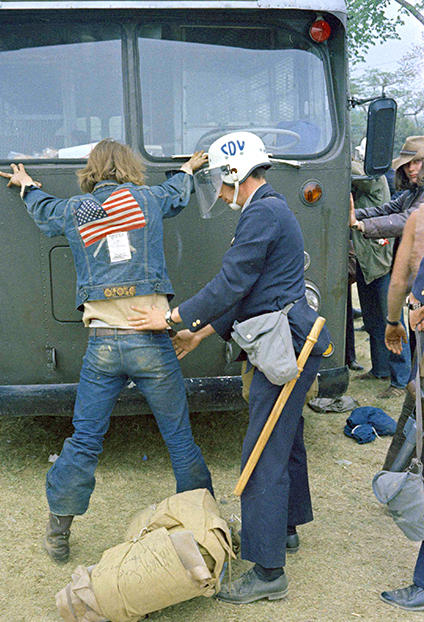 A policeman frisking a protestor