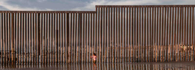 kid at beach by border wall