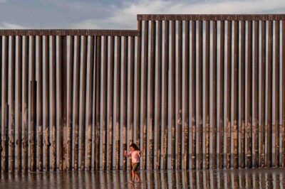 kid at beach by border wall