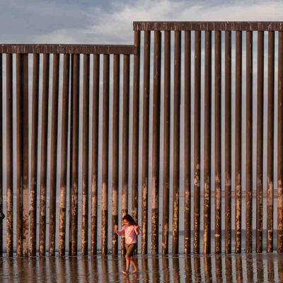 kid at beach by border wall