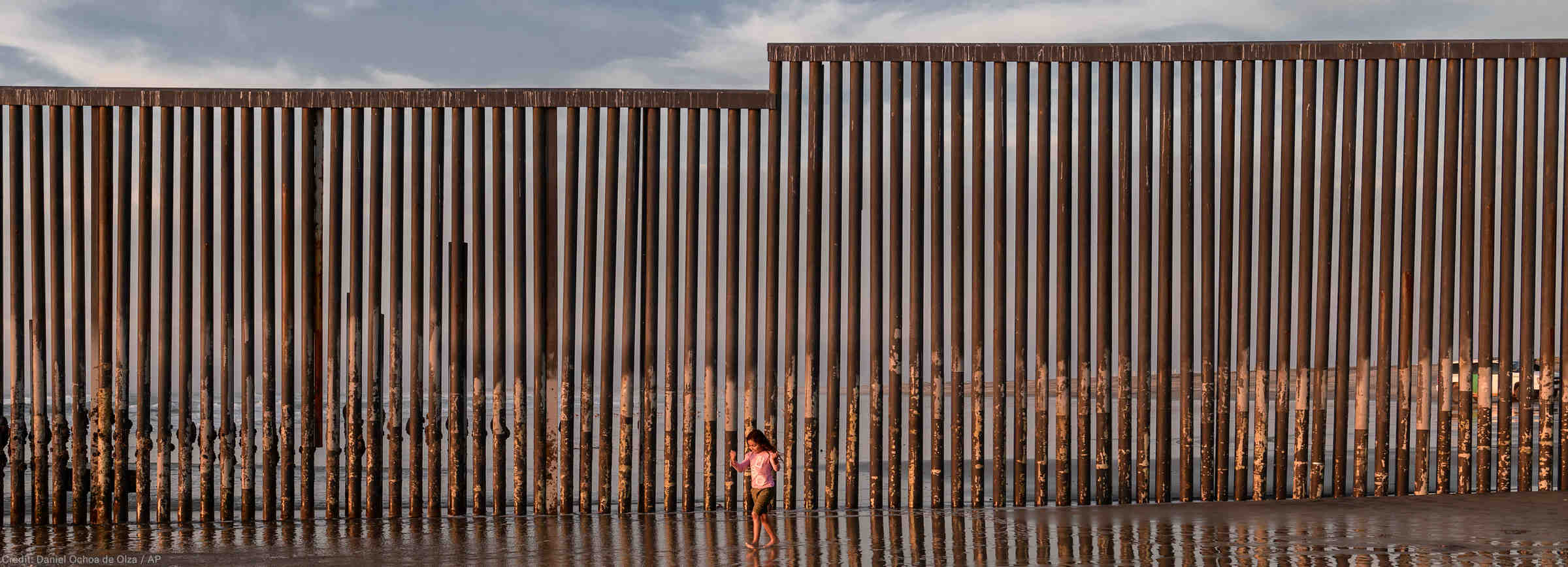 kid at beach by border wall