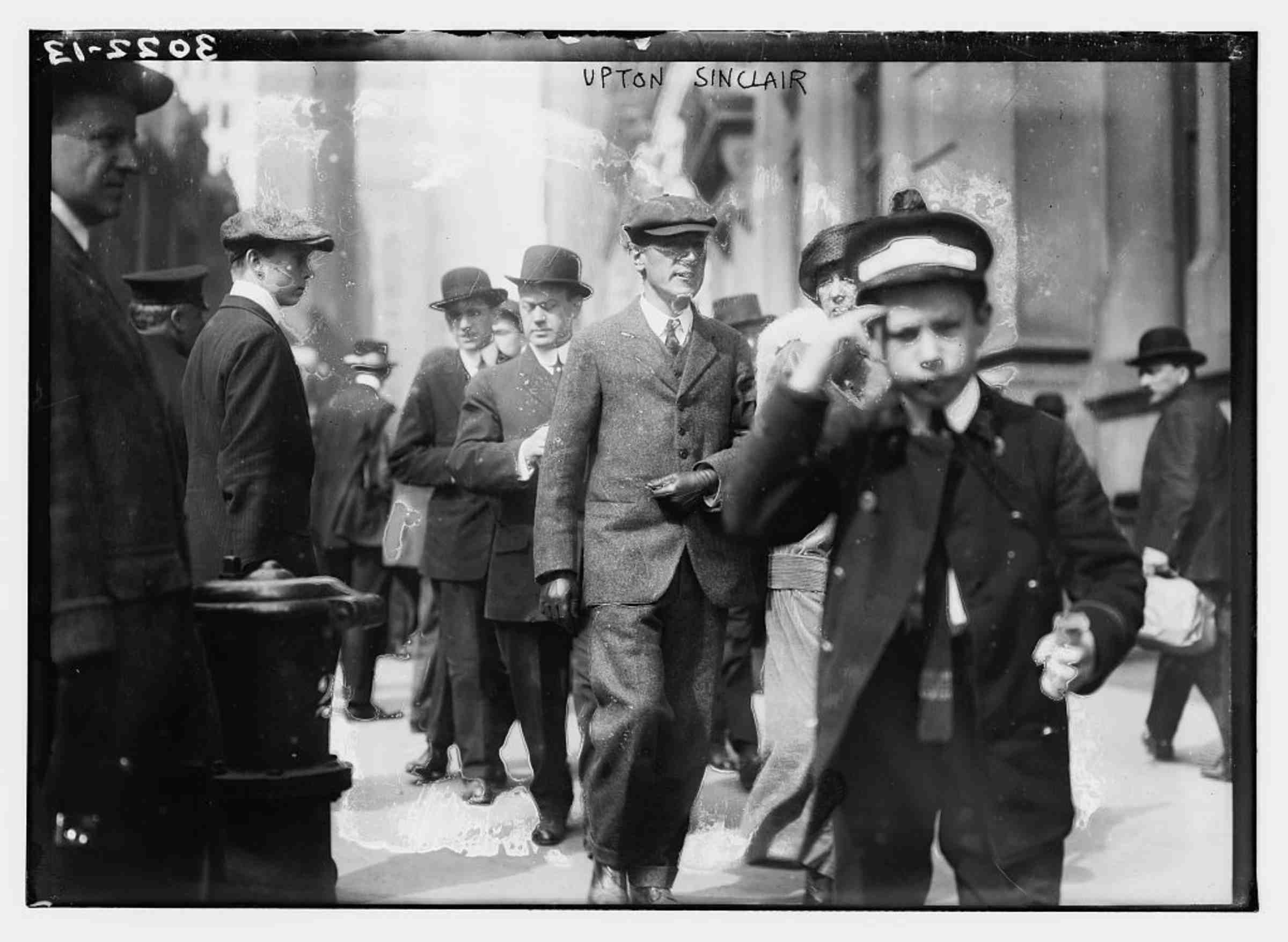 A distressed photograph of Upton Sinclair walking among others