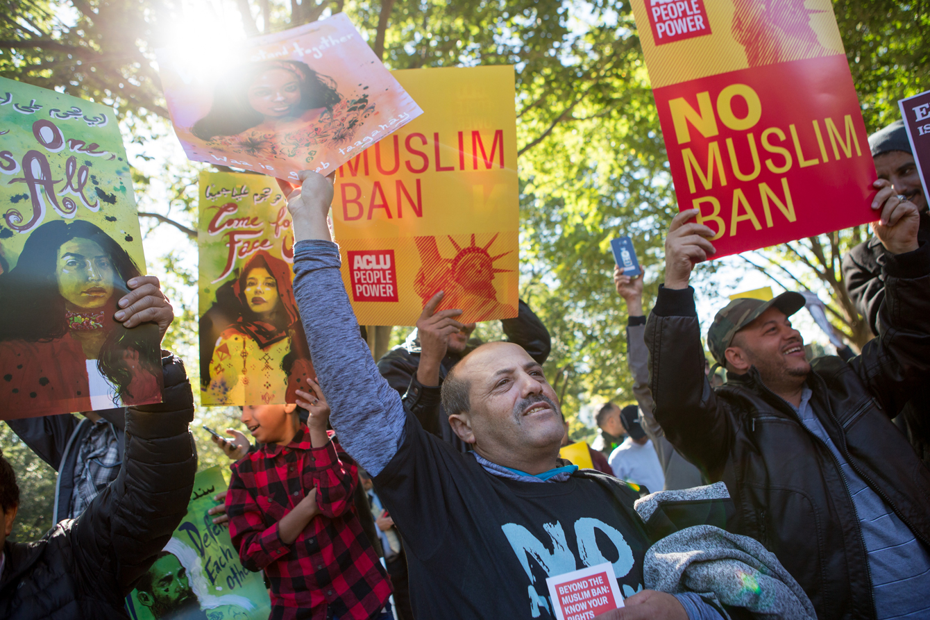 Protestors holding signs, including ACLU branded "NO MUSLIM BAN" posters