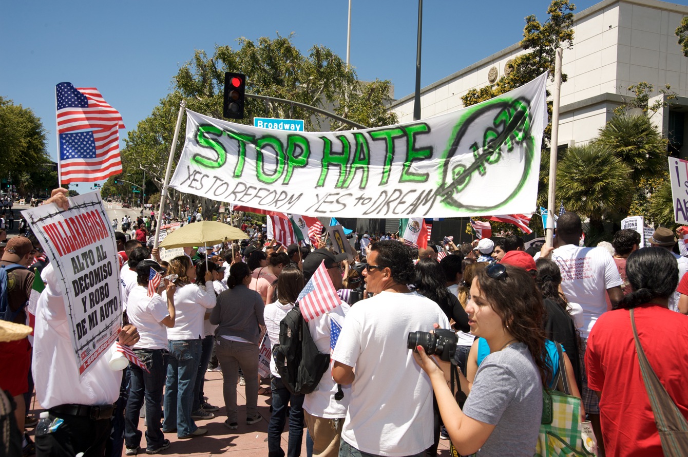 A crowd of people, some carrying a large banner that reads "Stop Hate: Yes to Reform Yes to Dream"