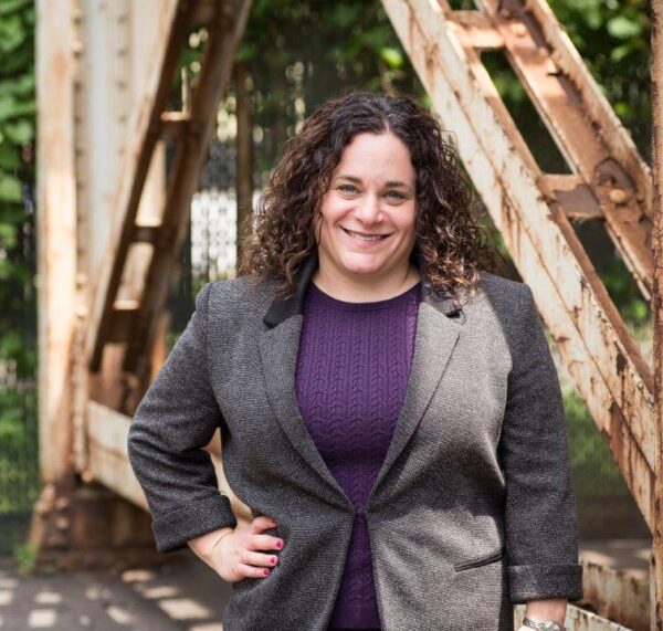 Headshot of Keren Zwick, director of litigation of Chicago's National Immigrant Justice Center. She is smiling with a hand on her hip