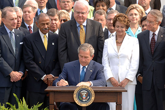 George W. Bush signing legislation in front of a crowd of people