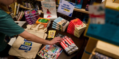 A hand reaches for a book among banned books.