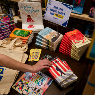 A hand reaches for a book among banned books.