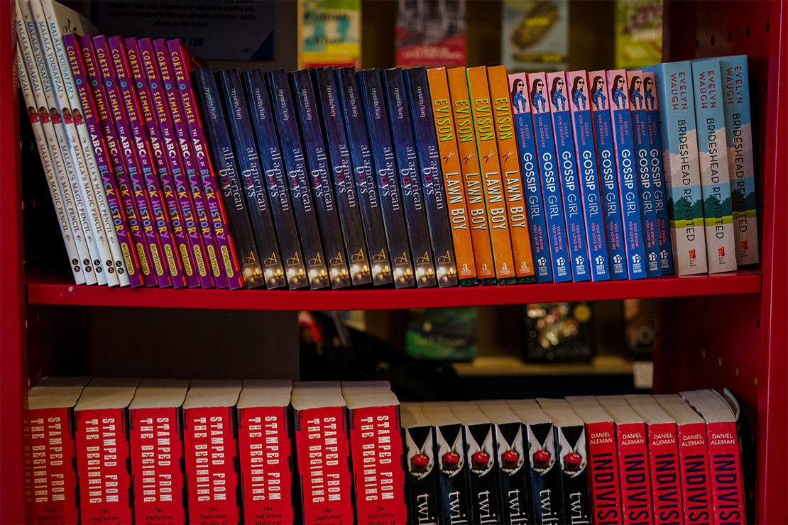 A red book caddy on wheels with a set of banned books on its shelves.
