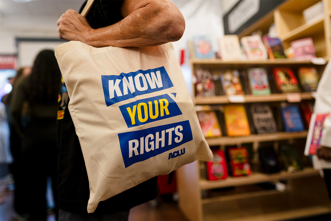 Person carrying a tote bag reading "KNOW YOUR RIGHTS TO READ BANNED BOOKS ACLU."