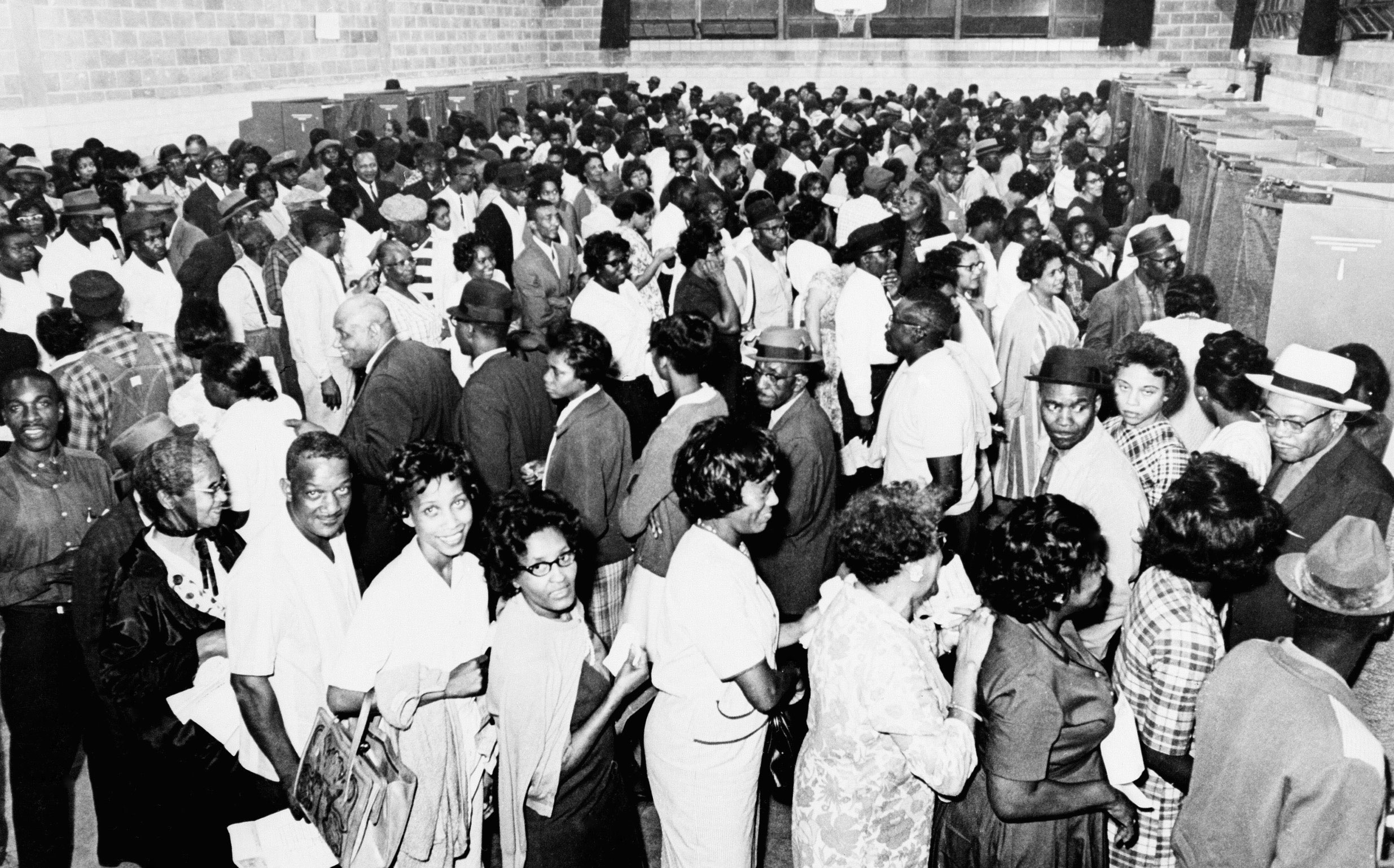 A historical image of a long line of Black voters waiting to vote