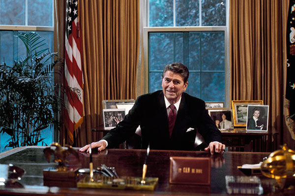 Ronald Reagan sitting behind his desk