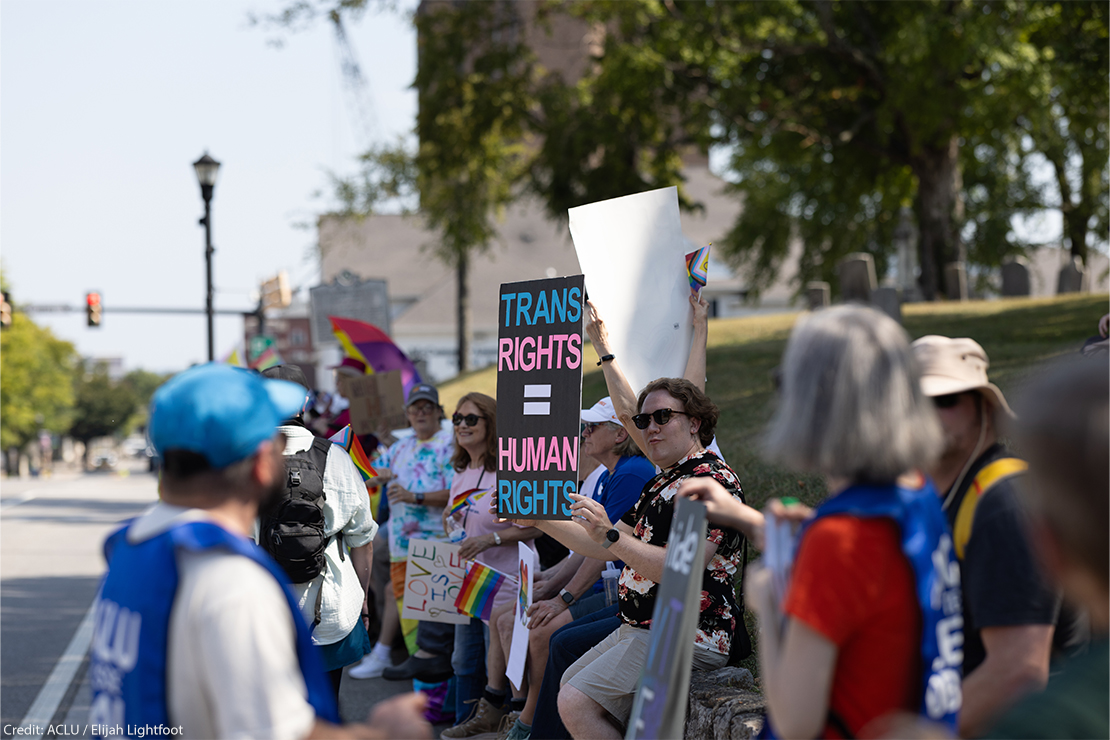 Demonstrators carrying a sign reading "TRANS RIGHTS = HUMAN RIGHTS".