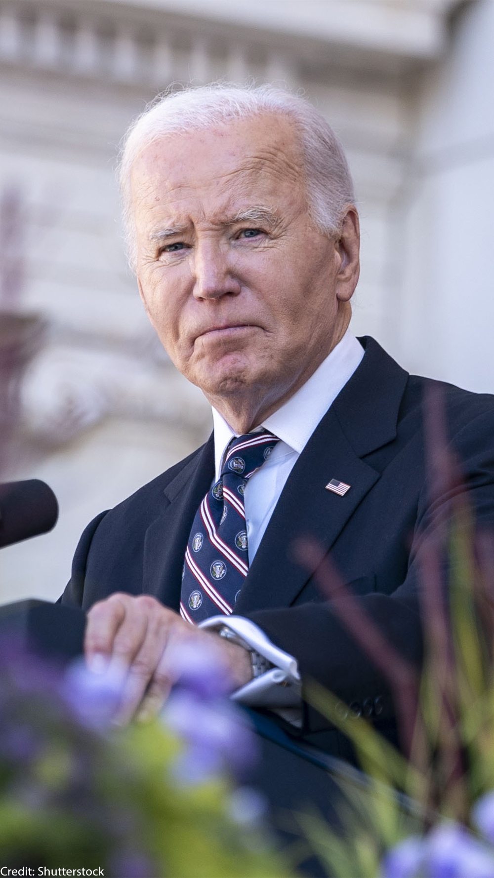 President Biden stares into the camera from behind a podium.