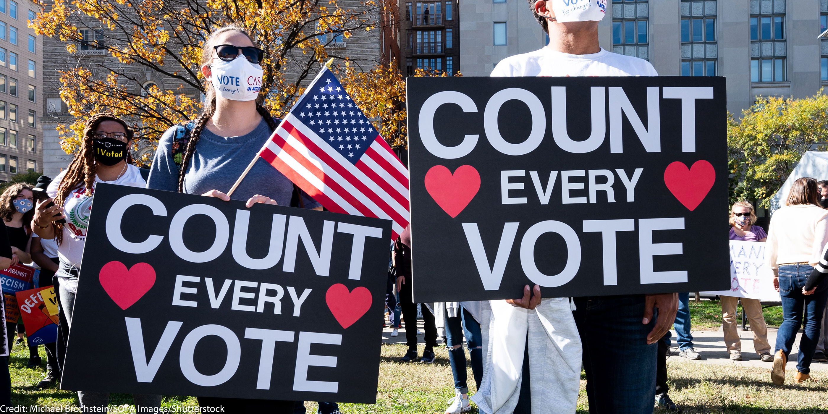 Two masked people hold signs that read "COUNT EVERY VOTE."