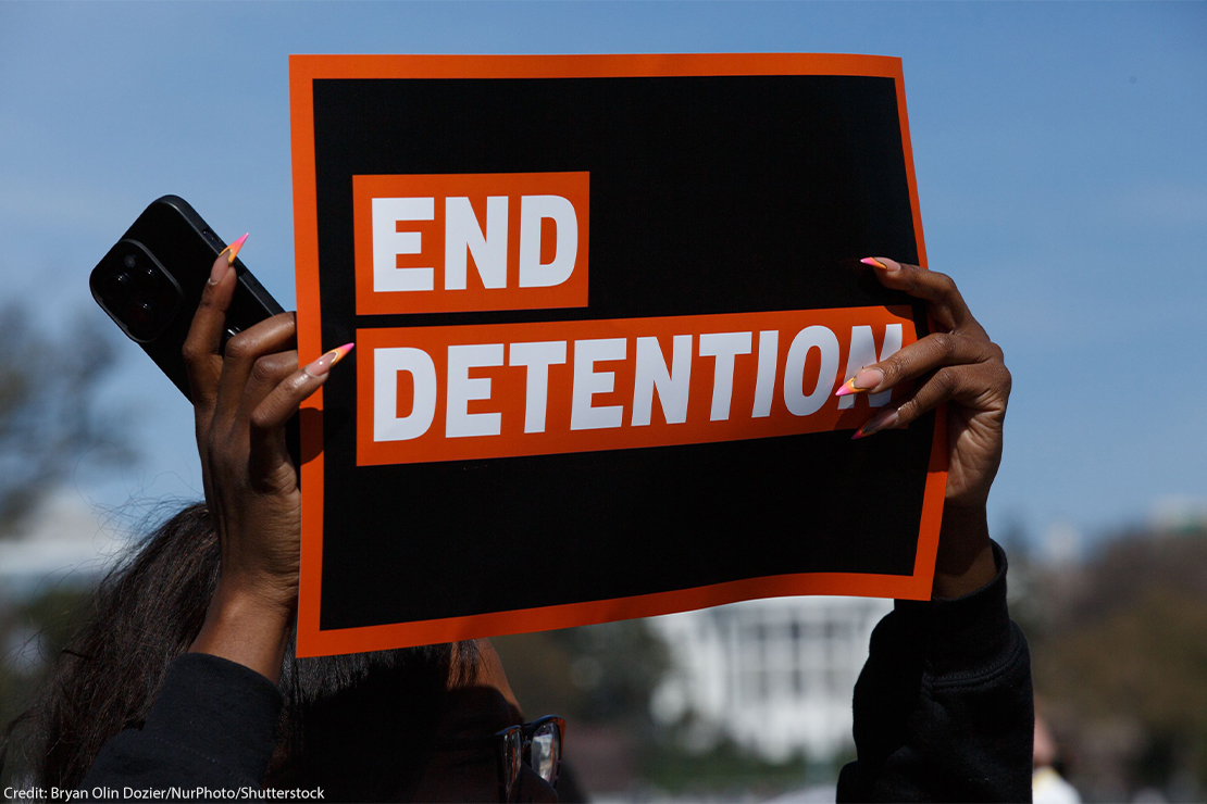 A person holding an ACLU sign reading "END DETENTION".