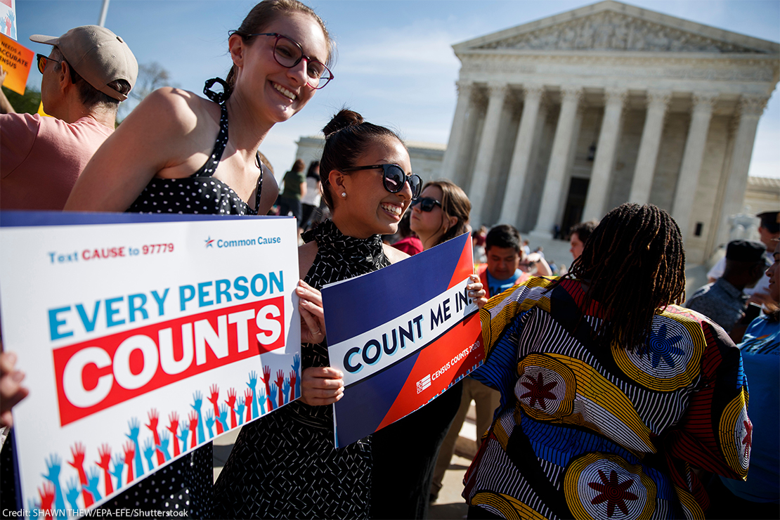 Protestors standing in front of the Supreme Court and holding signs reading "Every Person Counts" and Count Me in".