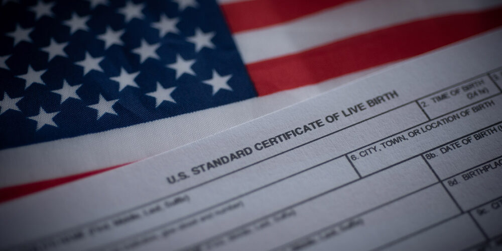 A birth certificate in front of an American flag.