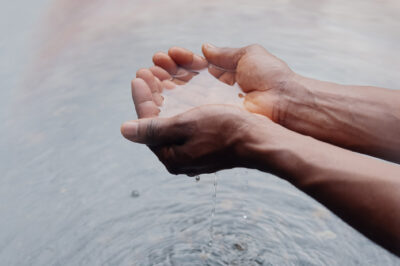 Two hands holding water, creating ripples on the surface below.