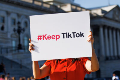 A person is holding a sign outside the Capitol Building that reads " #Keep TikTok".