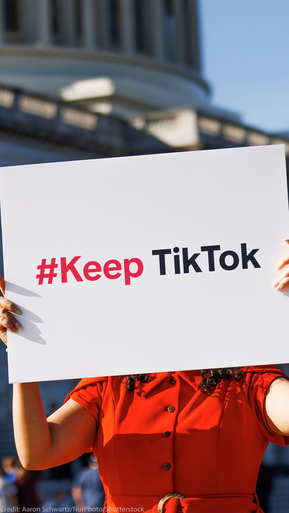 A person is holding a sign outside the Capitol Building that reads " #Keep TikTok".