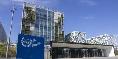 An exterior view of the International Criminal Court In The Hague, Netherlands, with the sign of with of the official logo and inscription of the International Criminal Court in the foreground.