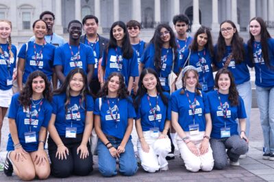 A group of high school students wearing blue shirts reading "DISSENT IS PATRIOTIC" pose for the camera.