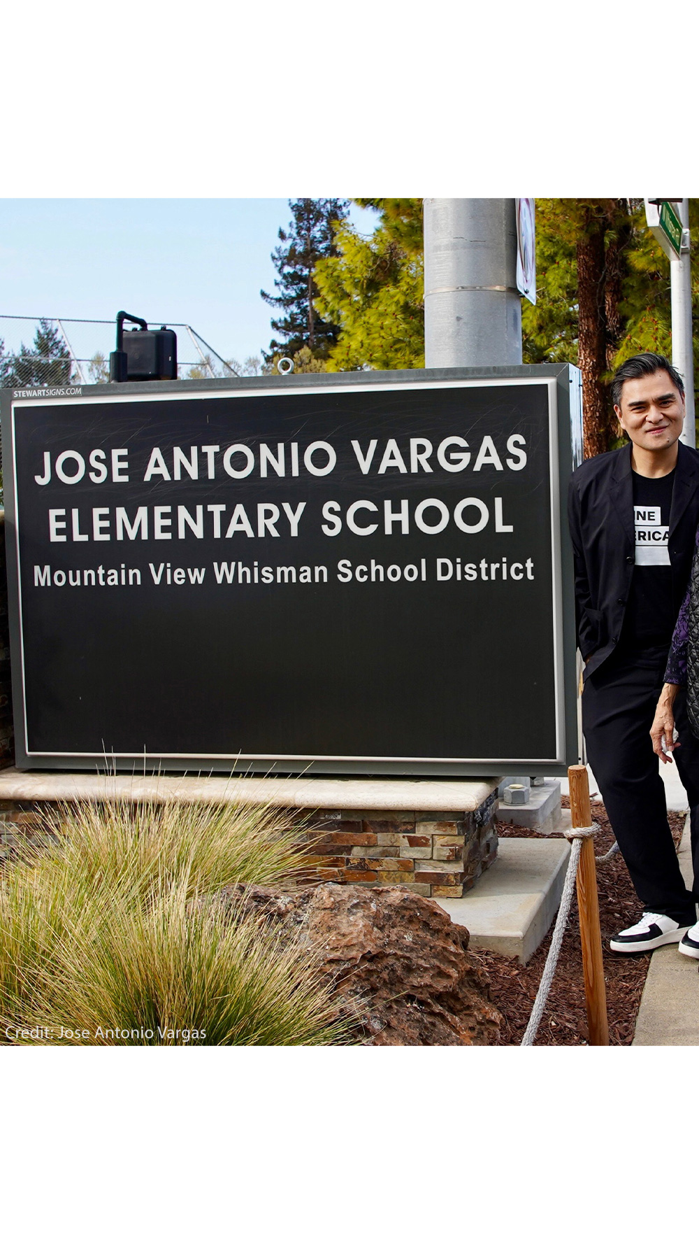 A smiling Jose Antonio Vargas and two equally joyful female family members stand to the right of a large sign that reads "JOSE ANTONIO VARGAS ELEMENTARY SCHOOL Mountain View Whisman School District".