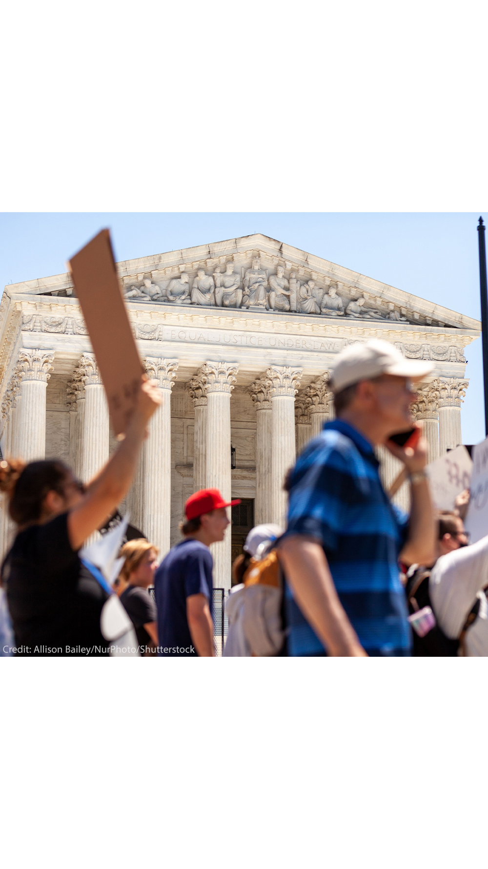 Pro-choice demonstrators (whose faces and signs are blurred) march in front of the Supreme Court and the statement on its facade, "Equal justice under law".