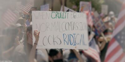 A demonstration sign that say "When Cruelty Becomes Normal, Compassion Looks Radical."