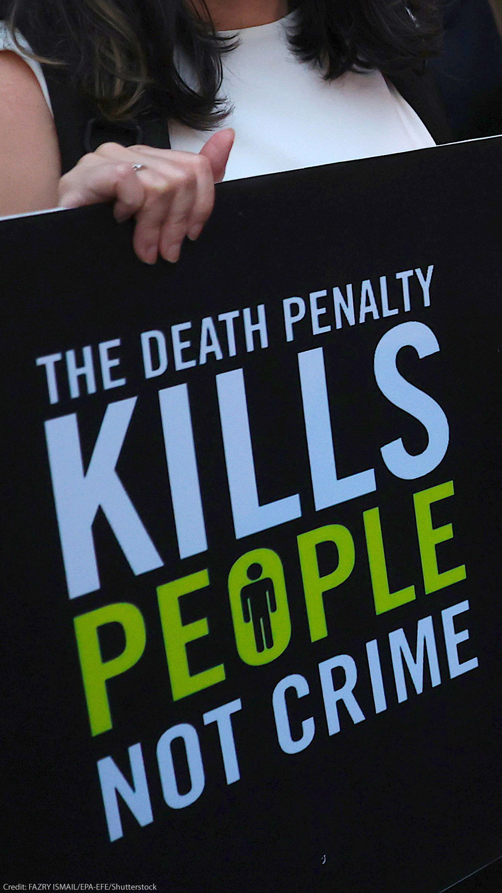 A demonstrator holds a sign that reads "THE DEATH PENALTY KILLS PEOPLE NOT CRIME."