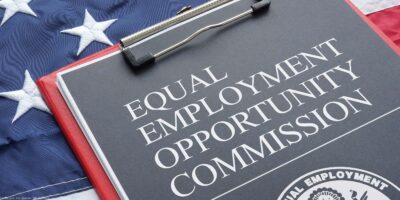 An Equal Employment Opportunity Commission document on a red clipboard that rests on an American flag.