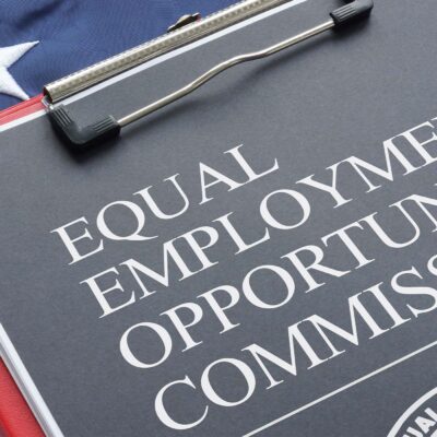An Equal Employment Opportunity Commission document on a red clipboard that rests on an American flag.