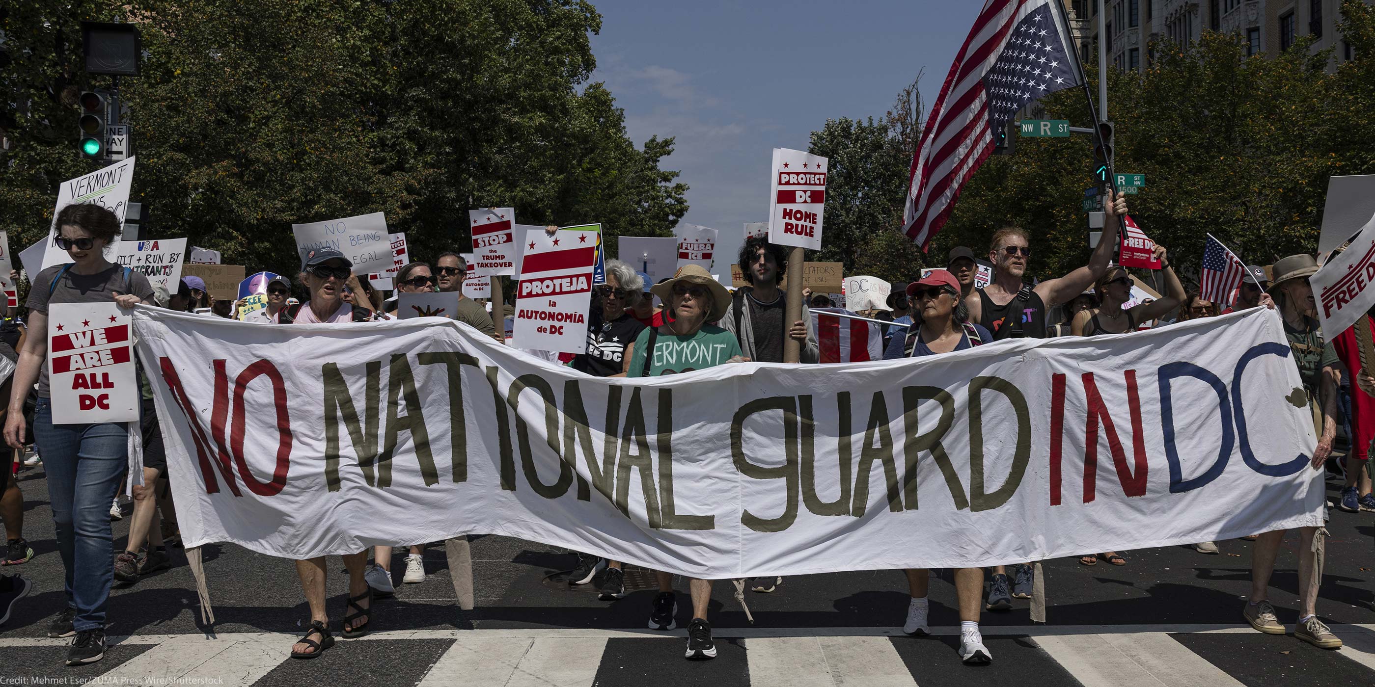 Demonstrators march in Washington, DC carrying a banner that reads " NO NATIONAL GUARD IN DC".