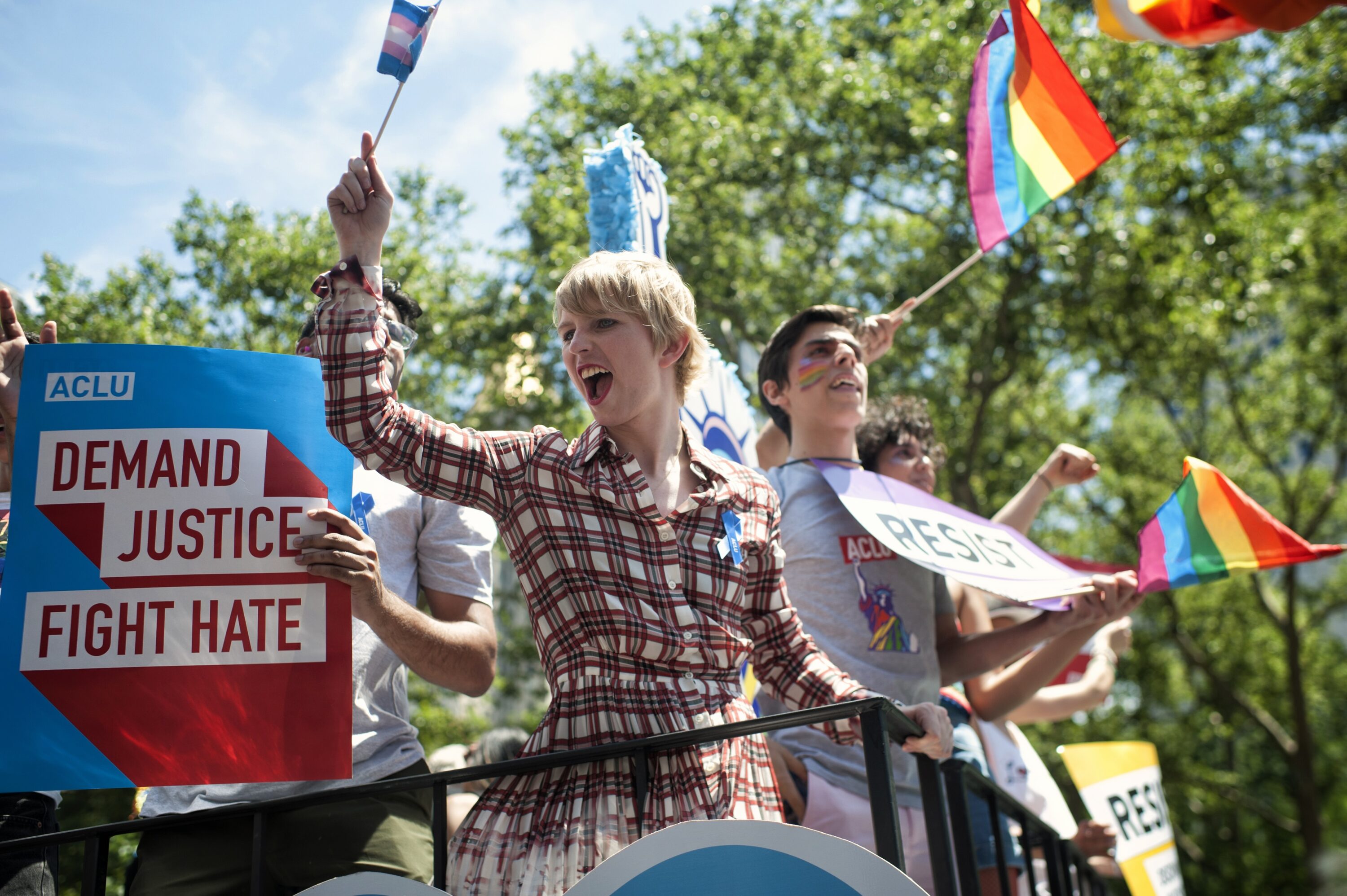 Chelsea Manning stands on a float at the NYC pride parade, waving a transgender pride flag.
